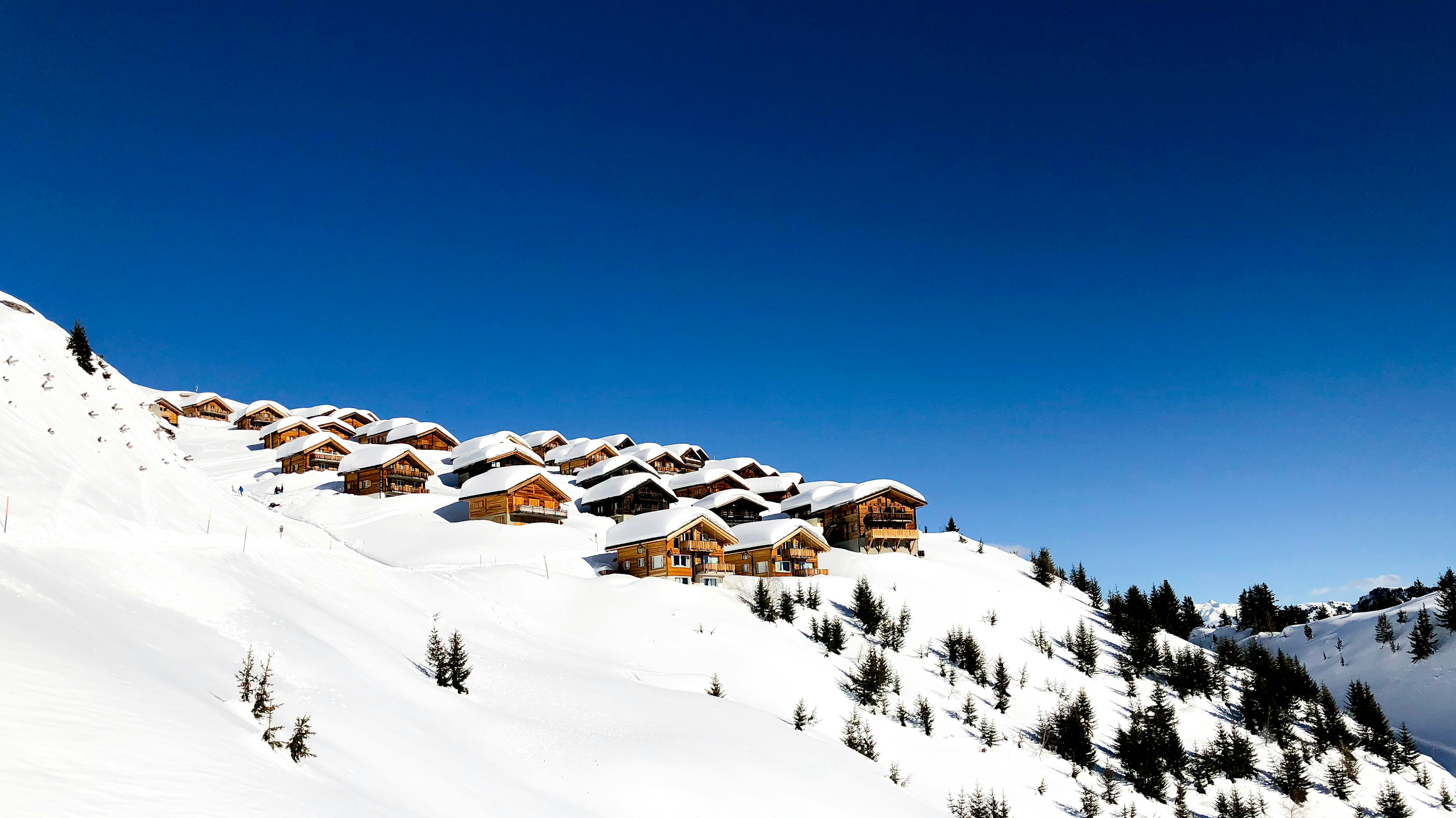 snow covered mountain with houses and trees during daytime